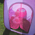Little girl sitting in tent behind the pink mesh curtain.